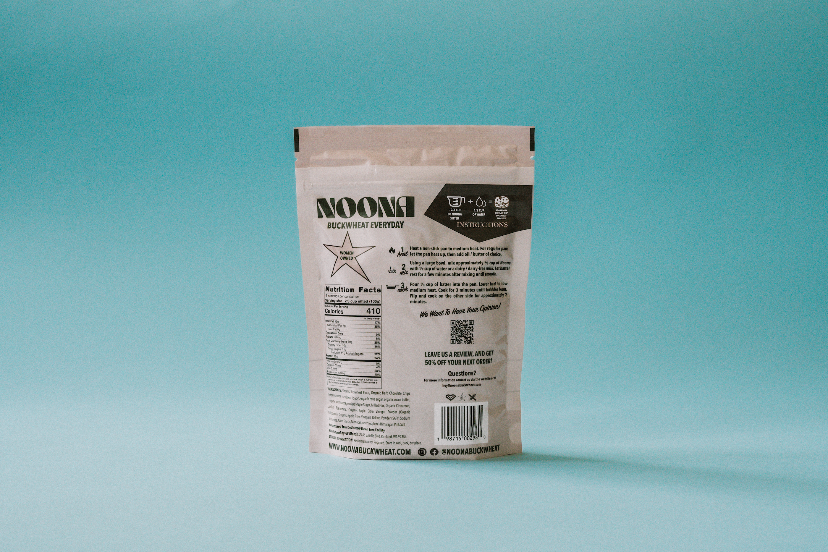 **Alt Text:**
The back of Noona's Dark Chocolate Chip Buckwheat Pancake Mix packaging, set against a vibrant blue background. The detailed nutrient label is clearly visible, listing the calories, protein, fiber, and other key nutritional information. The ingredients list highlights real, wholesome ingredients like buckwheat flour and dark chocolate chips. Instructions for making the pancakes are also displayed, with simple step-by-step directions for adding water and cooking.